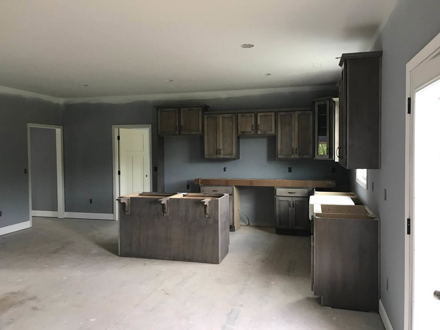 Kitchen with natural wood cabinets, matching wood countertops, stainless steel hardware, and a black waste container near the cabinetry.