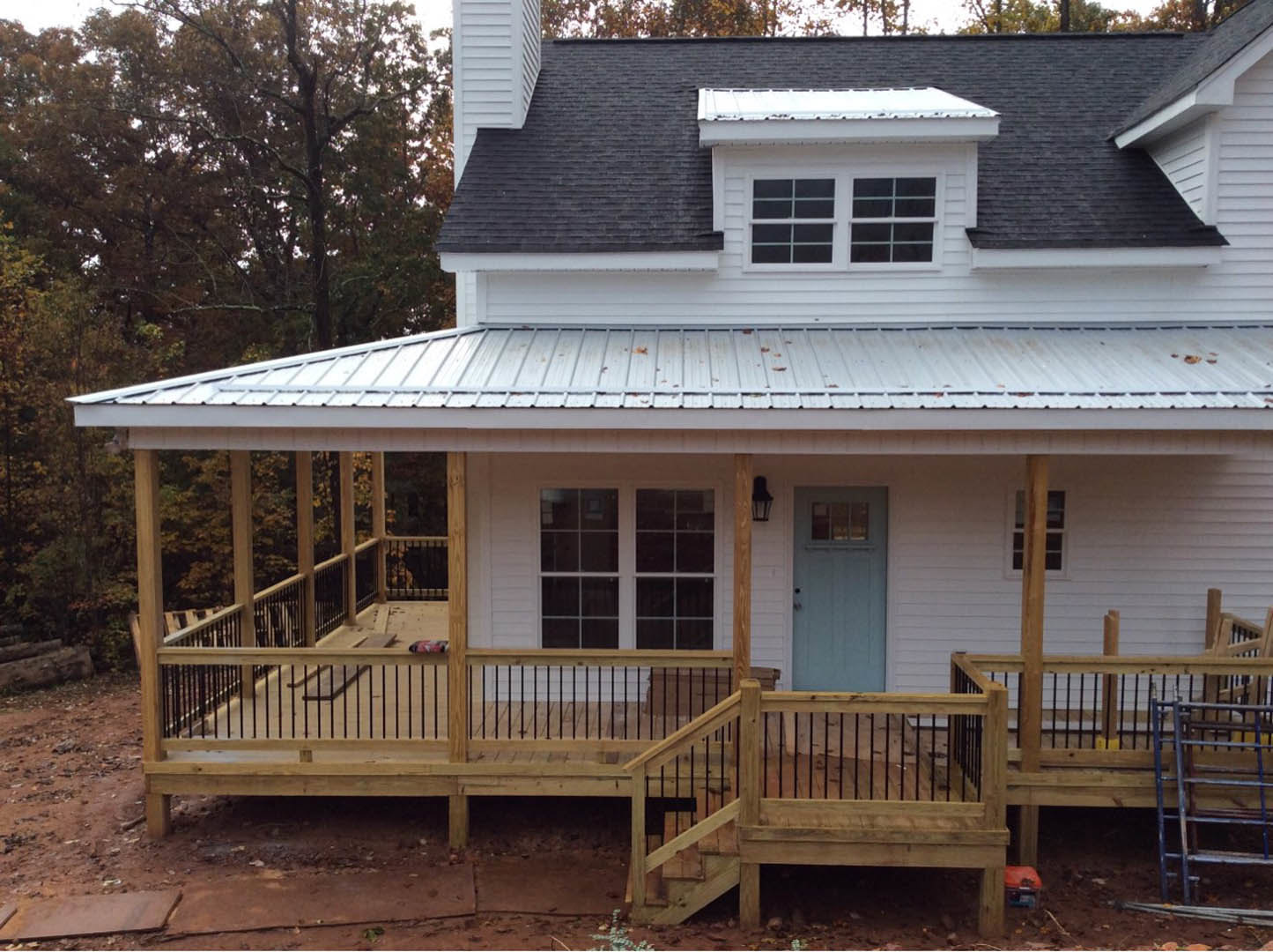 Wooden porch with stairs, white door featuring a window, yellow siding, deck with railing, tree in background