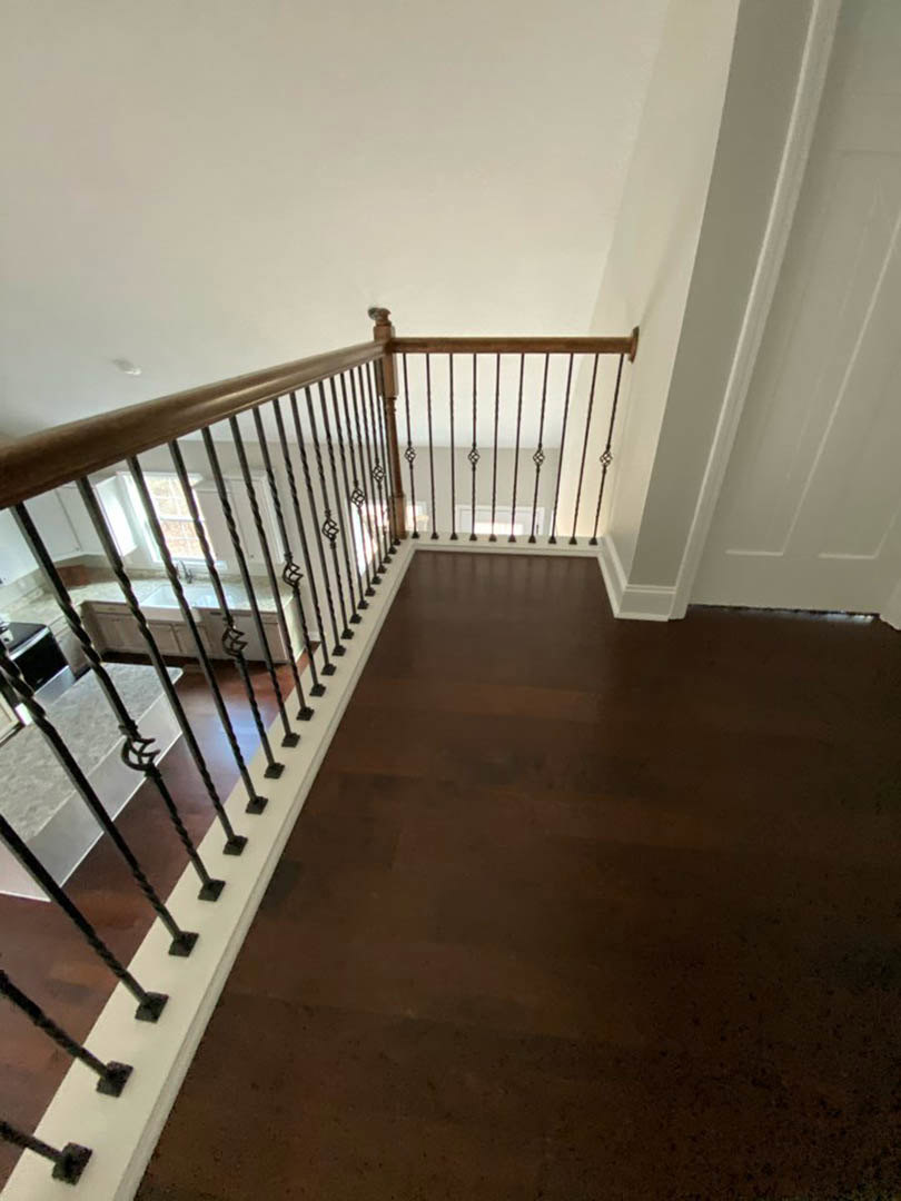 Staircase with medium brown wood flooring, white baseboards, and black metal railings against white walls