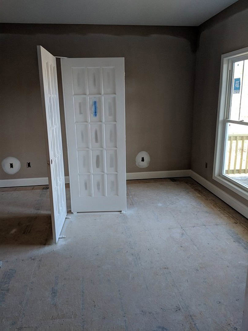 White door with blue paint, white-framed window, light plaster walls, wood flooring in residential interior