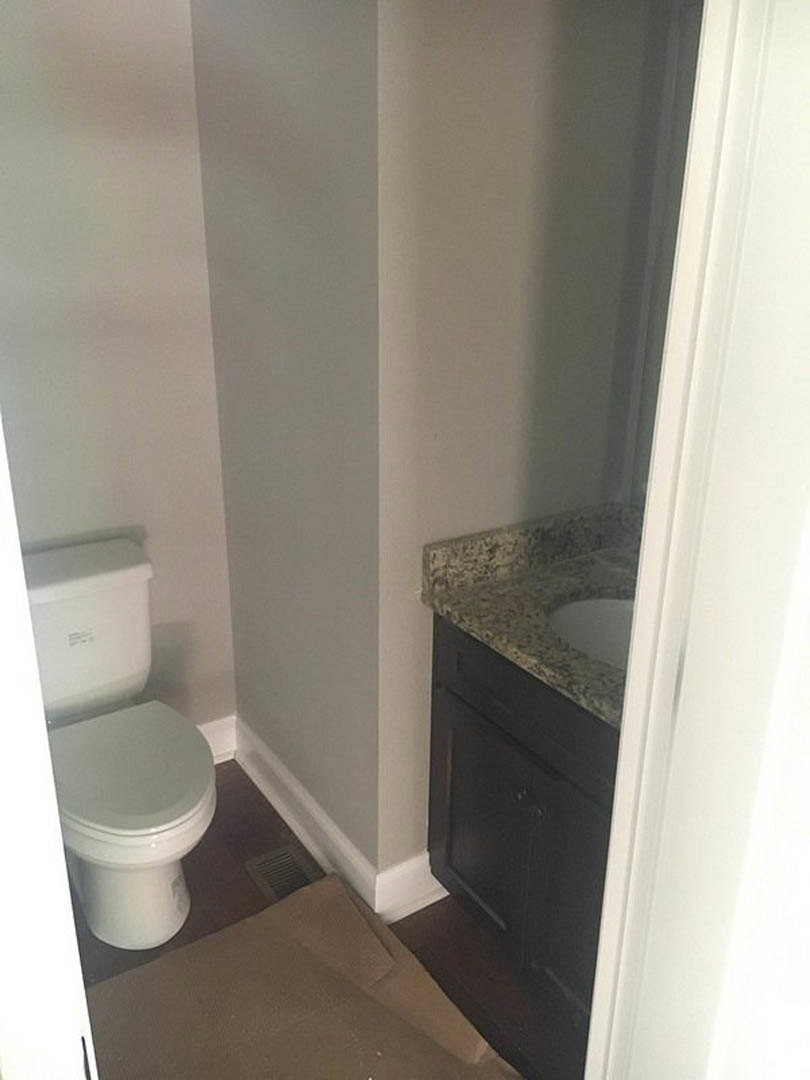 Modern bathroom with white toilet, rectangular sink, light tile flooring, and smooth plaster walls