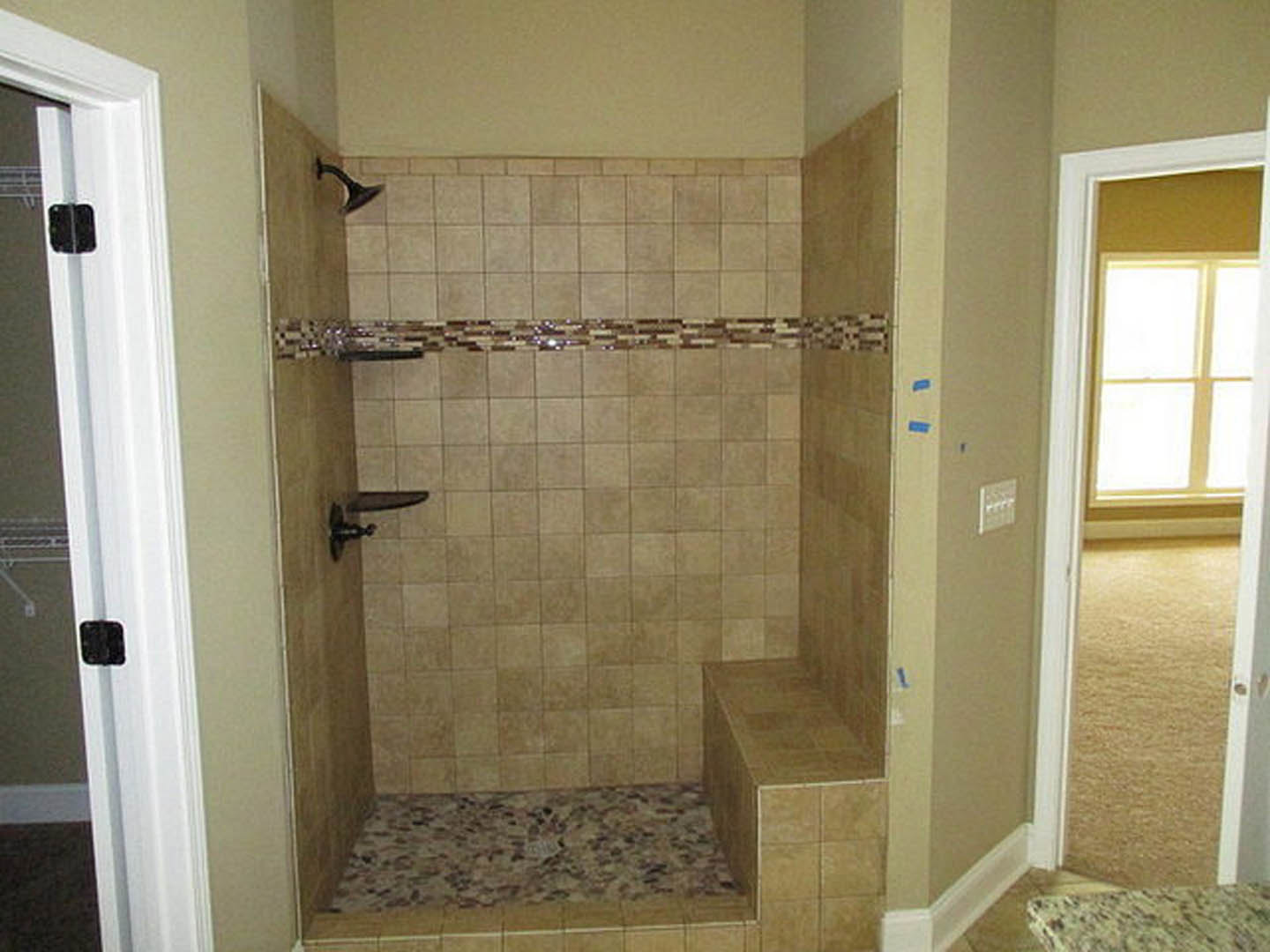 Walk-in shower with large-format gray tile walls, glass door, chrome plumbing fixtures, and matching tile floor in a modern bathroom