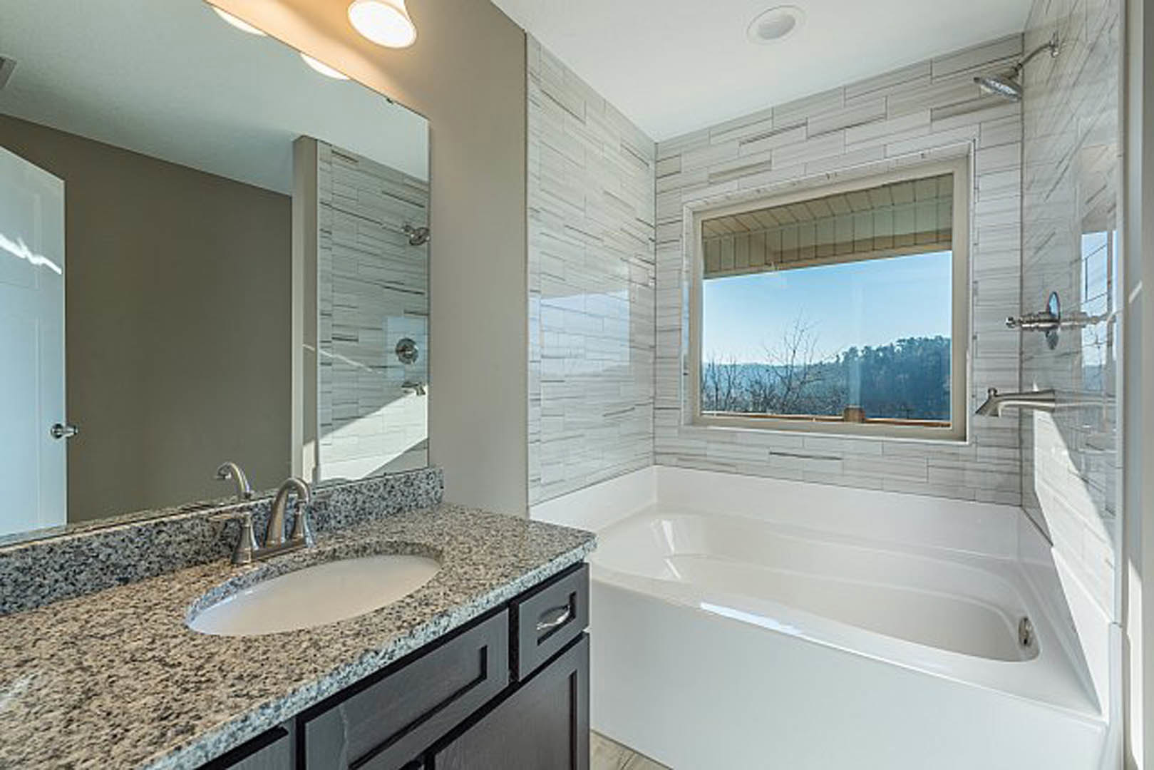 Modern bathroom featuring a freestanding bathtub, white vessel sink on a stone countertop, tiled walls, chrome faucet, and neutral finishes