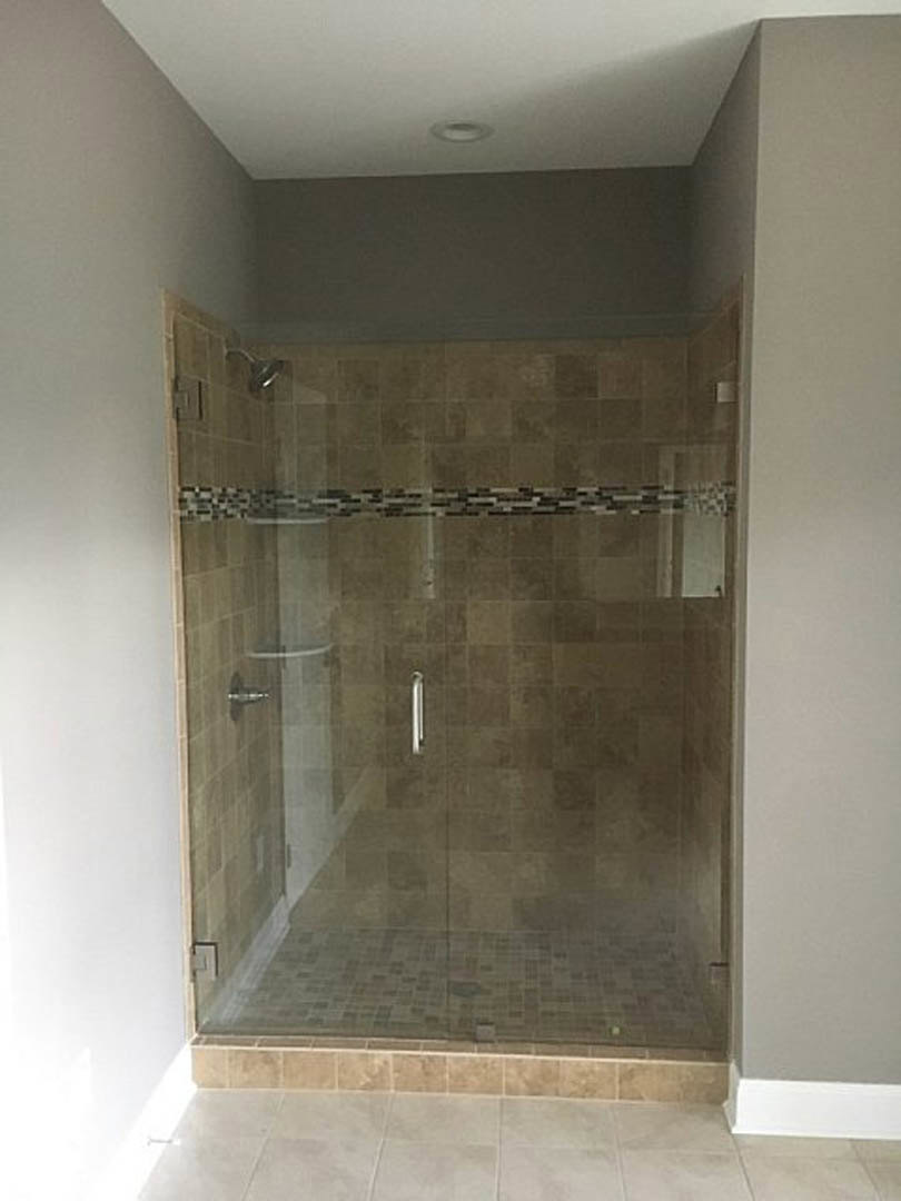 Glass shower enclosure with marble tile flooring and plaster walls in a modern bathroom.