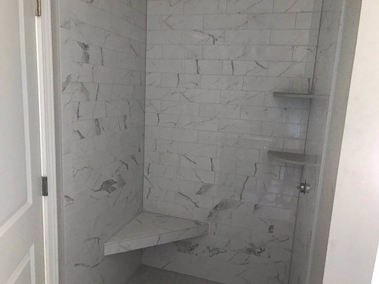 Shower interior featuring a marble tile wall with white and gray veining