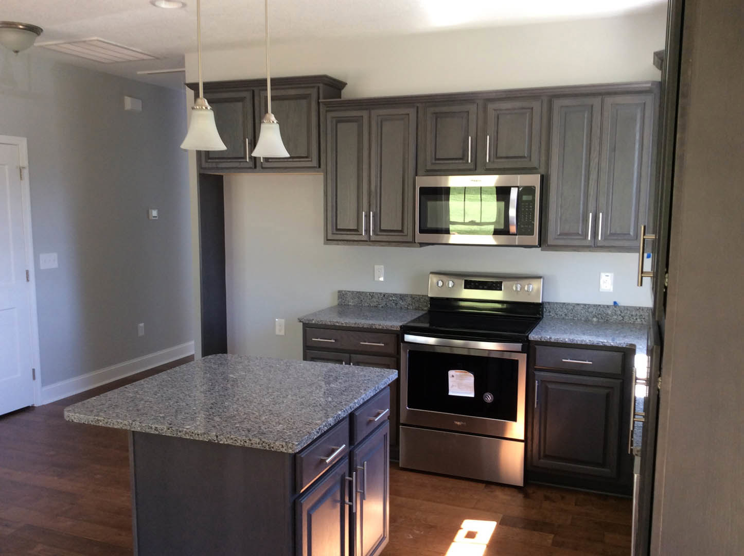 Granite countertops with stainless steel stove, white cabinetry, built-in microwave, and hinged white door in a modern kitchen