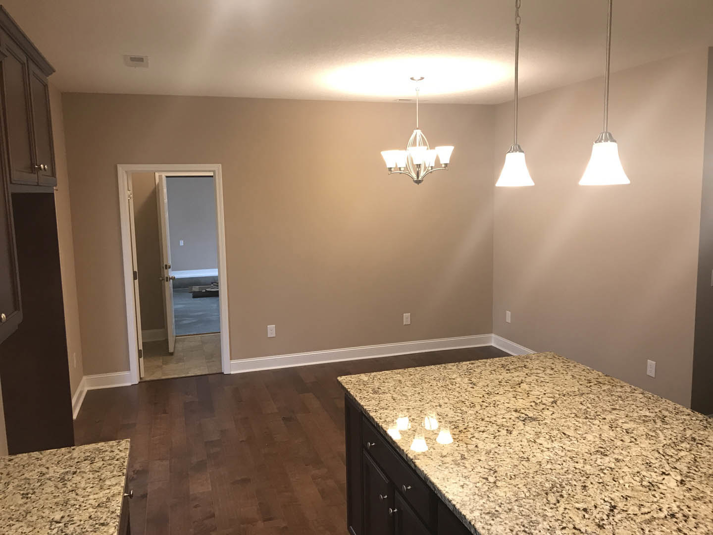 Kitchen with marble countertop, wood flooring, white cabinetry, stainless steel sink, and modern chandelier overhead