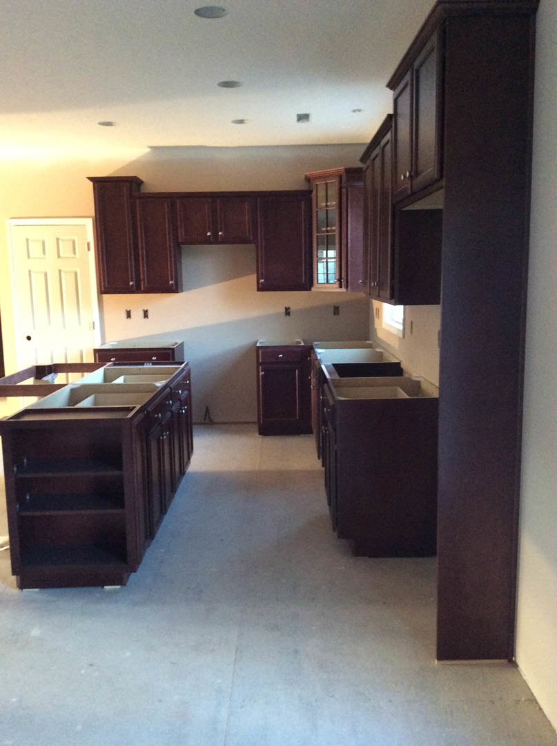 Kitchen with dark wood cabinets, kitchen island featuring open shelves, white door with cross design, window with glass panes, silver knobs on cabinetry, light-colored countertops