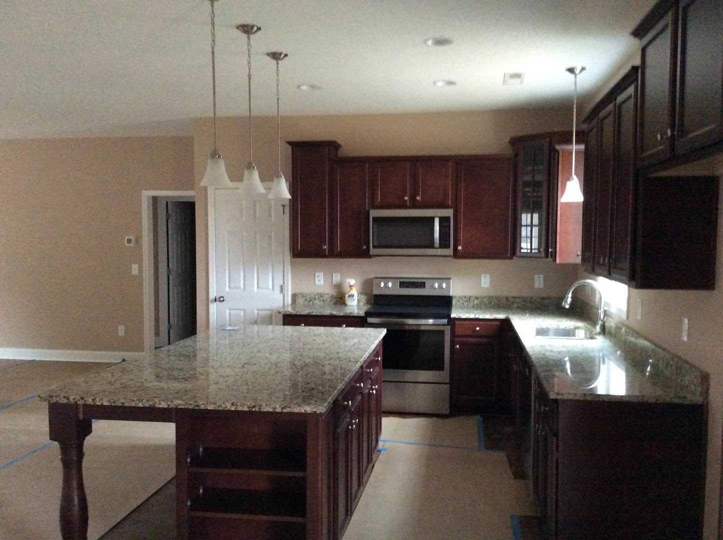 Granite countertops and dark wood cabinets in a modern kitchen with stainless steel appliances and a central island