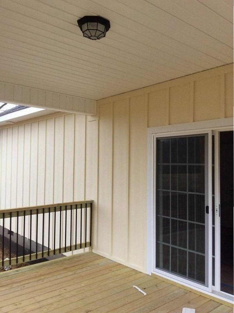 Wood deck with glass door and adjacent white door, metal railing, wood flooring, close-up of window, light fixture, and white electrical outlet