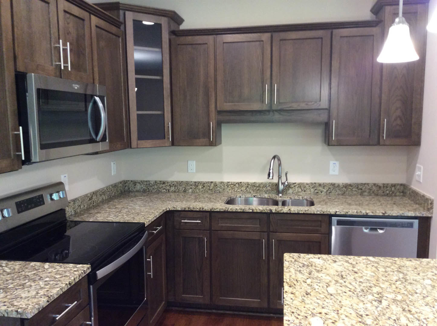 Granite countertops, wood cabinets, stainless steel stove and microwave, marbled backsplash, recessed lighting, kitchen window
