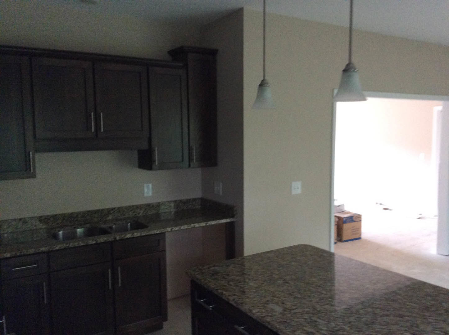 Granite countertops with tile backsplash, dark cabinetry, stainless steel sink, and built-in appliances in a modern kitchen