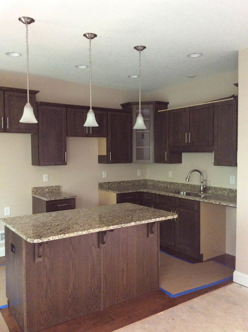 Kitchen with dark wood cabinets, granite countertops, silver faucet, and tile backsplash