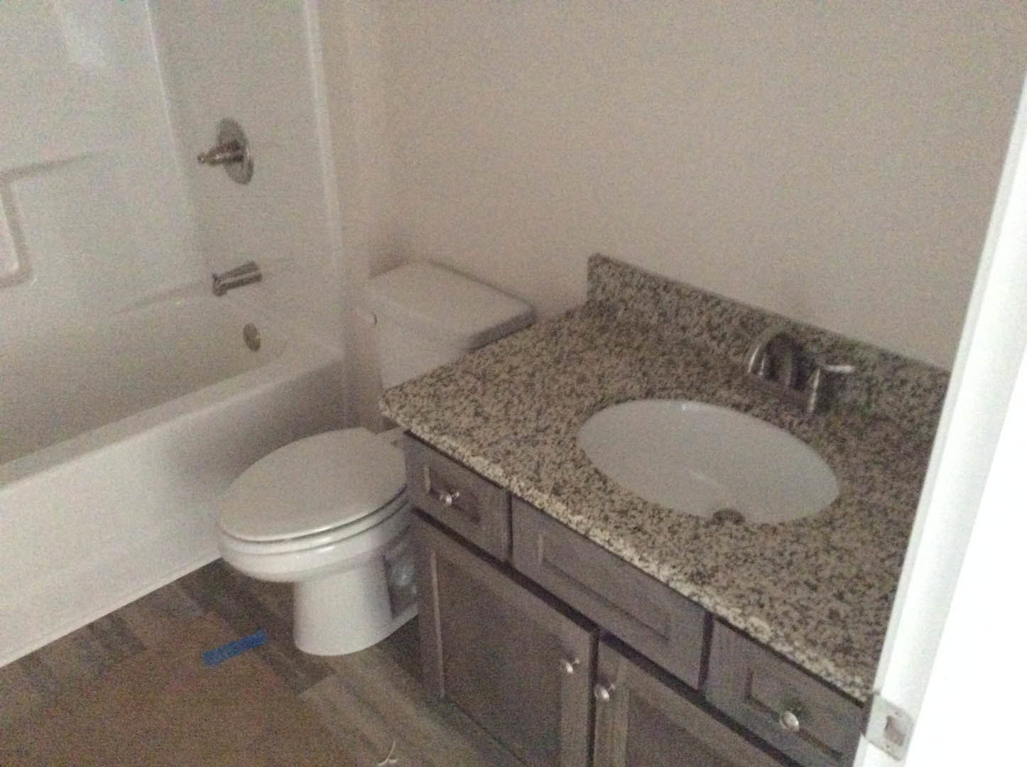 Bathroom with marble countertop, undermount sink, white toilet, and bathtub; light tile flooring, neutral walls, chrome fixtures