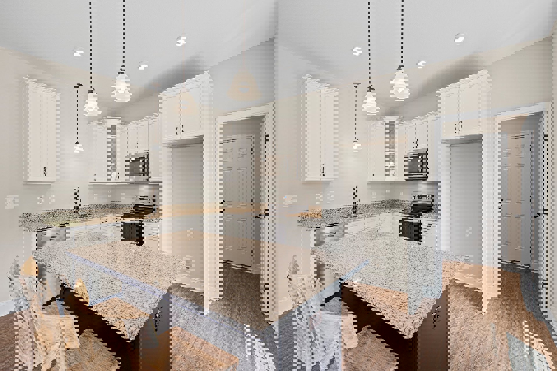 Marble kitchen island with waterfall edge, white cabinetry, stainless steel stove, built-in microwave, wood flooring, and wooden chair