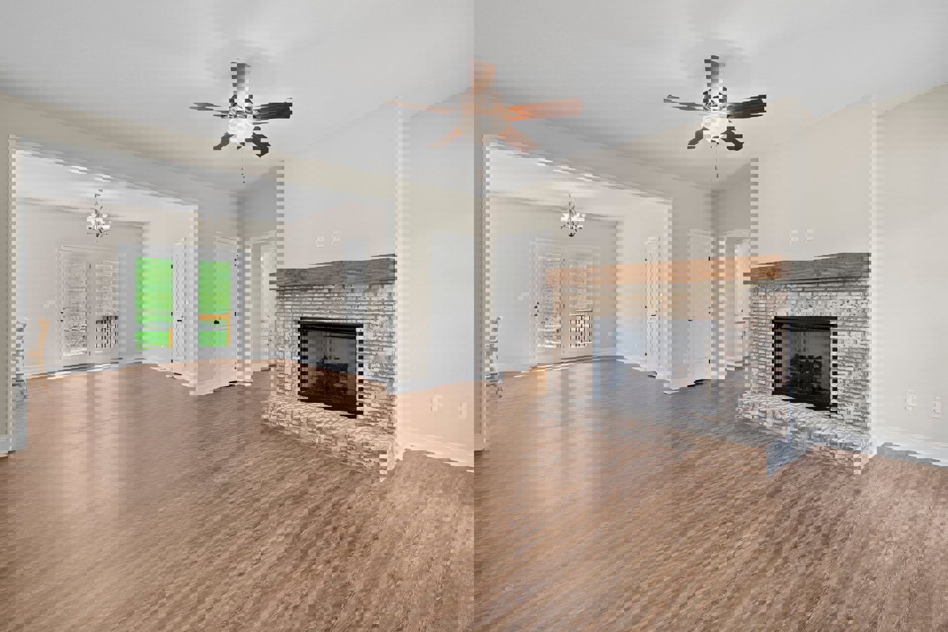 Living room with hardwood floors, stone fireplace burning wood, ceiling fan with light, white door featuring black knobs