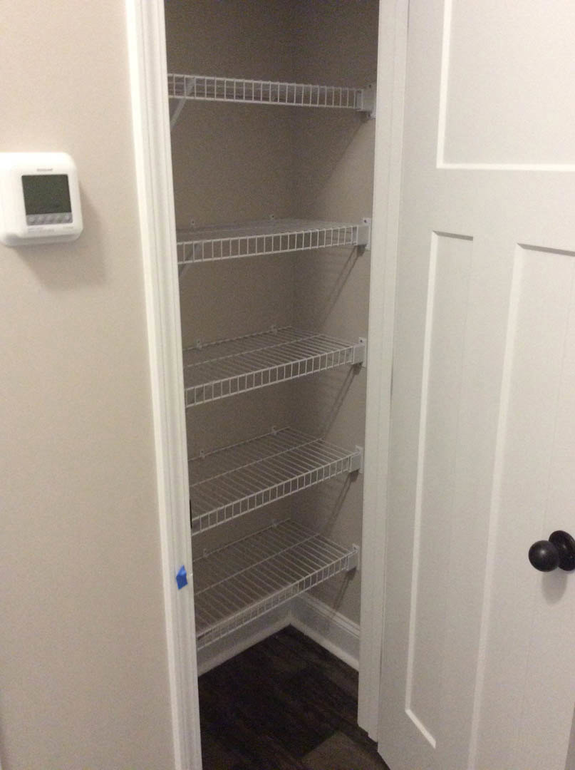 White closet interior with built-in shelves, dark wood flooring, and white trim