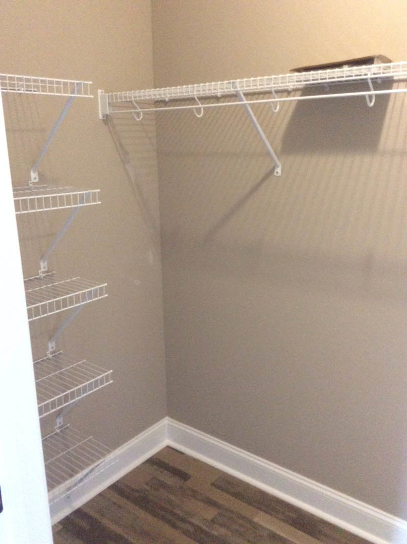 Closet with white metal shelving, shoe rack, and wood flooring with white baseboard