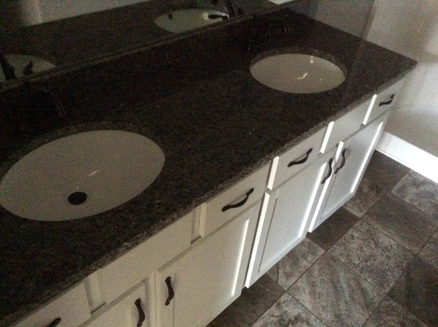 Bathroom with white cabinets, dual sinks, marble countertops, and black circular hardware on drawers