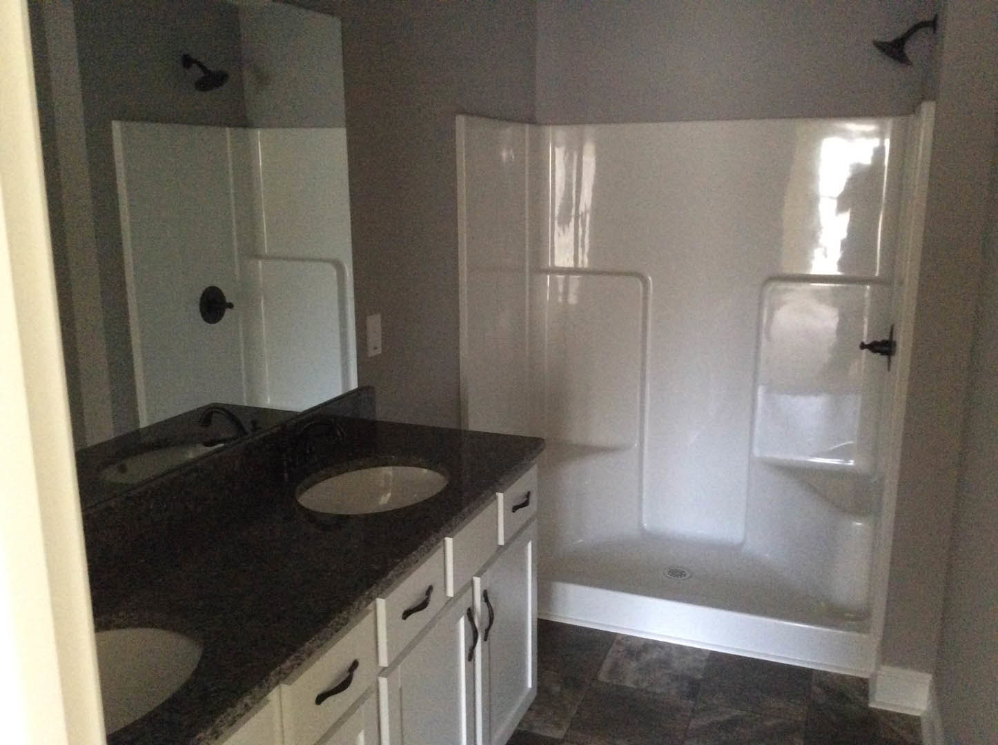 Modern bathroom featuring a white tile shower, black countertop vanity with integrated sink, and chrome fixtures.