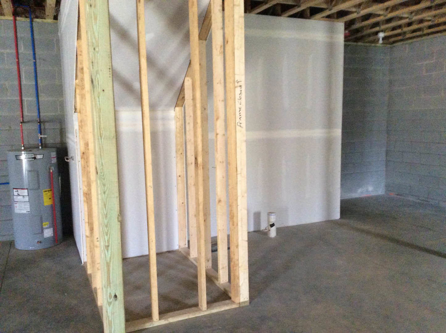 White plaster wall with exposed wood framing and beams, construction materials visible in unfinished room