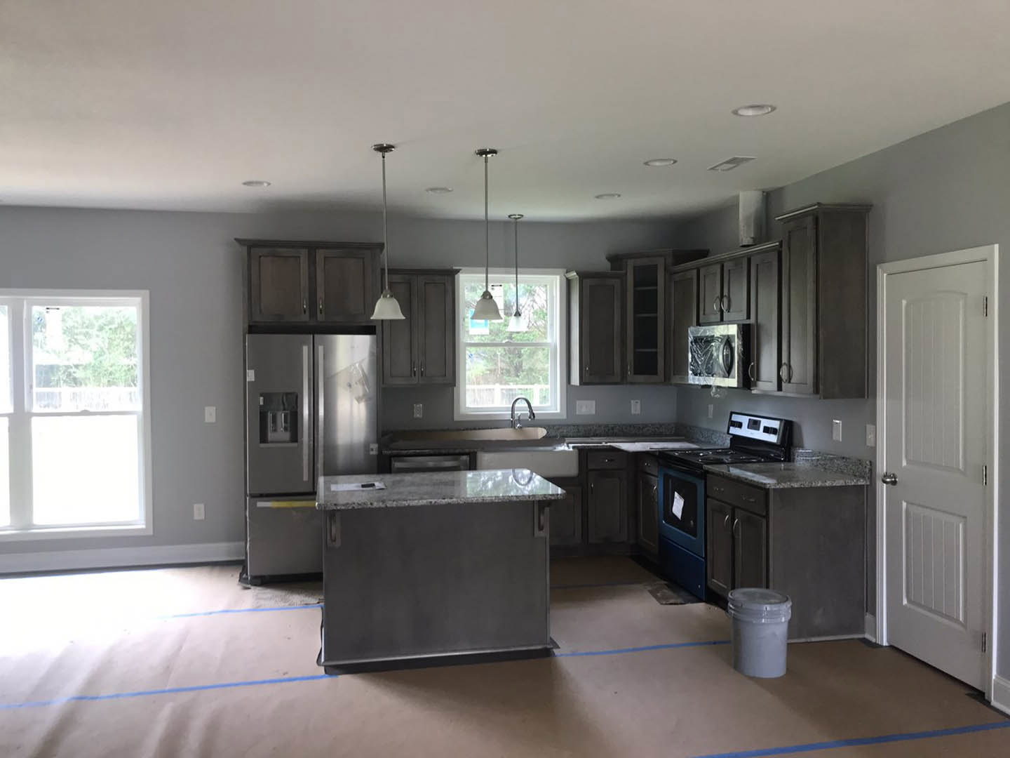 Modern kitchen featuring a white countertop, stainless steel refrigerator, undermount sink, white-framed window, and white cabinetry.