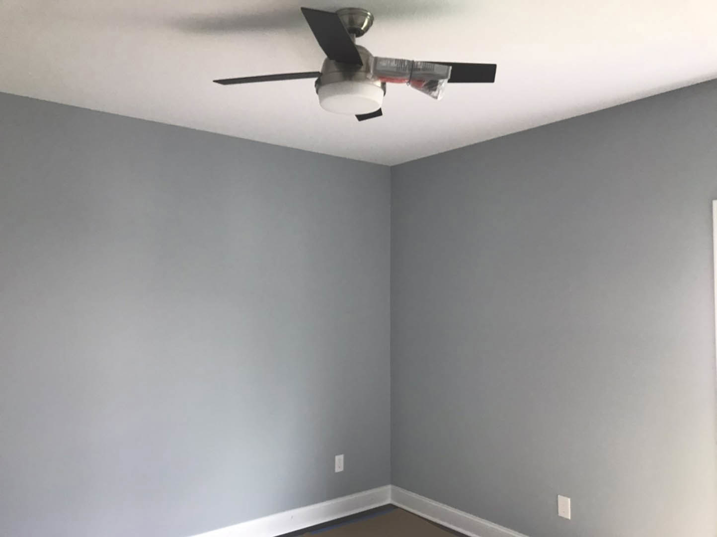 Ceiling fan with integrated light fixture mounted on white plaster ceiling in a modern residential room
