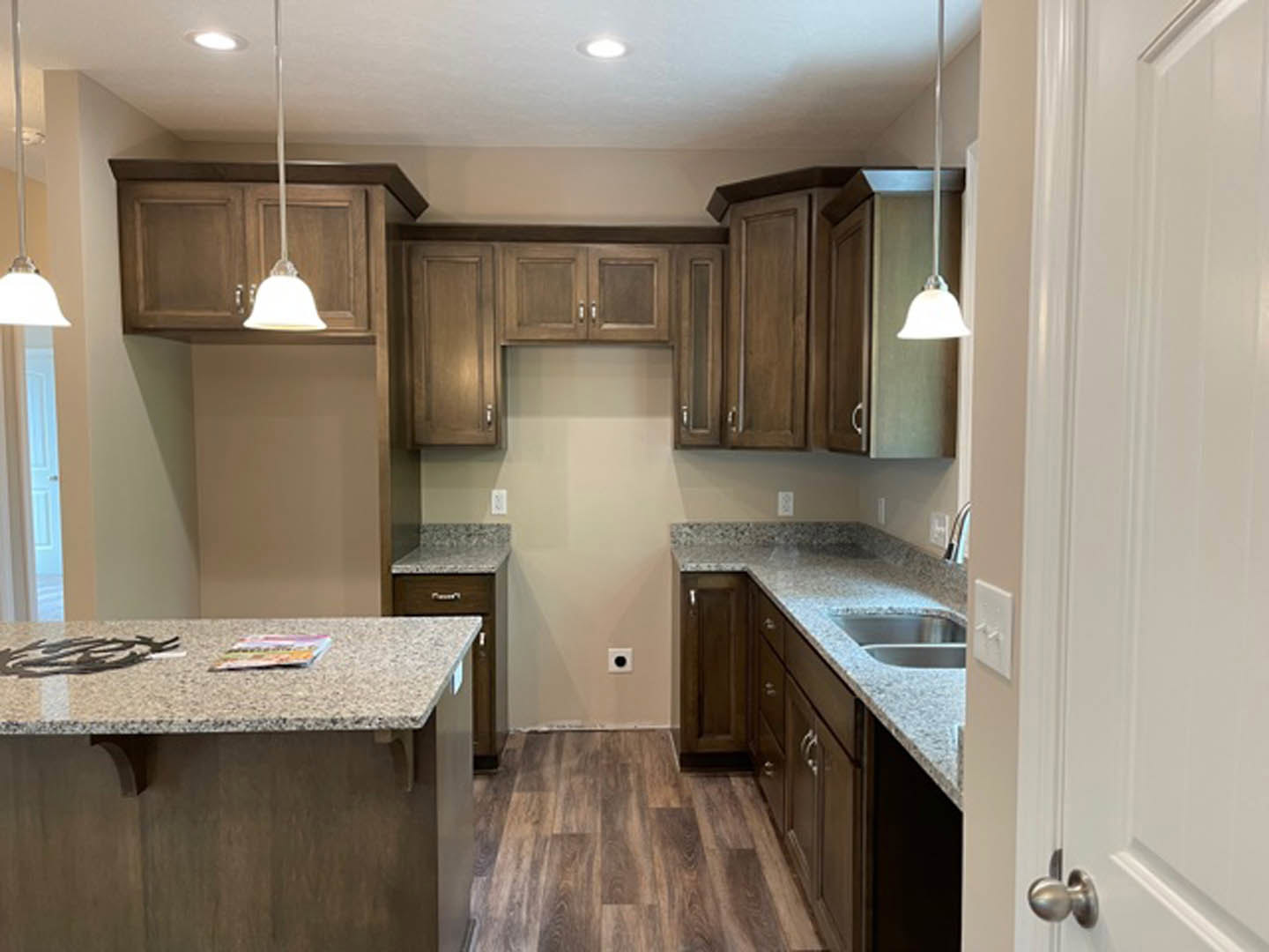Granite countertops with wood cabinetry, stainless steel appliances, undermount sink, and neutral tile backsplash in a modern kitchen