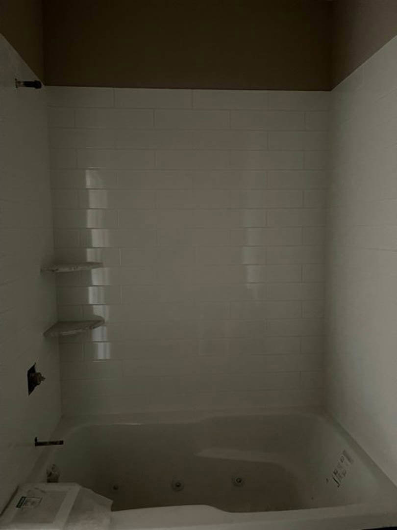 White tile shower with built-in shelf and chrome plumbing fixtures