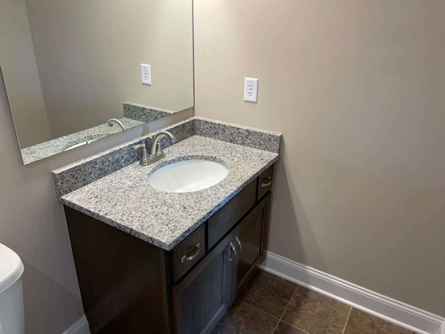 White bathroom sink with chrome faucet, rectangular mirror above, light-colored tile backsplash, and quartz countertop