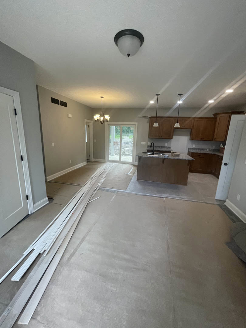 Modern kitchen with white cabinets, stainless steel sink set in a stone countertop, glass door with signage, ceiling-mounted light fixture, white door with black hinges, wood
