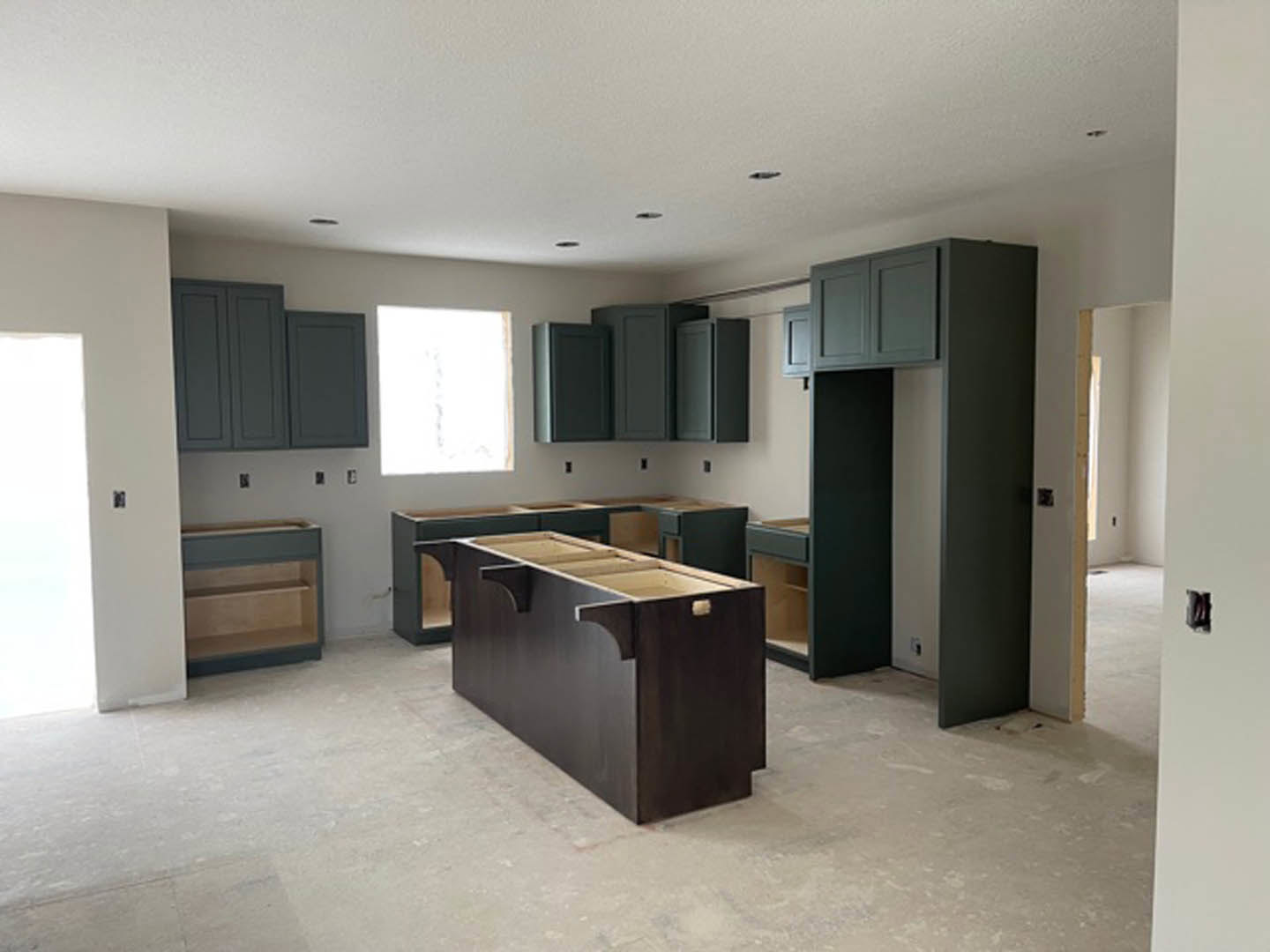 Modern kitchen featuring matte black cabinets and drawers, white quartz countertop, stainless steel sink, and recessed lighting above.