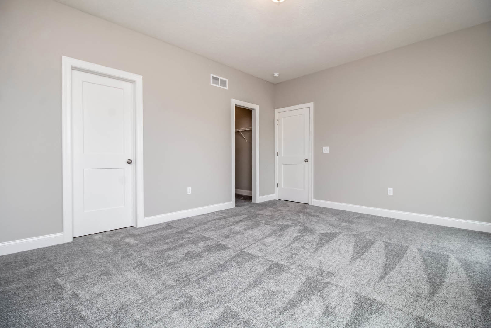 Grey carpeted floor, white paneled doors with silver handles, white-framed window, smooth white walls and ceiling