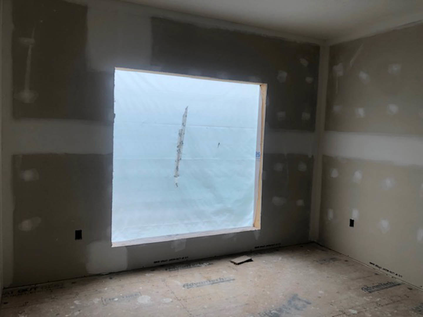 Sunlit room with smooth white plaster walls, large window, light wood floor, and simple ceiling detailing