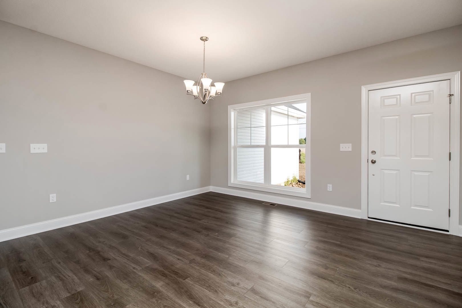 Hardwood floor room with white walls, black trim, white-framed window, white door, and modern chandelier