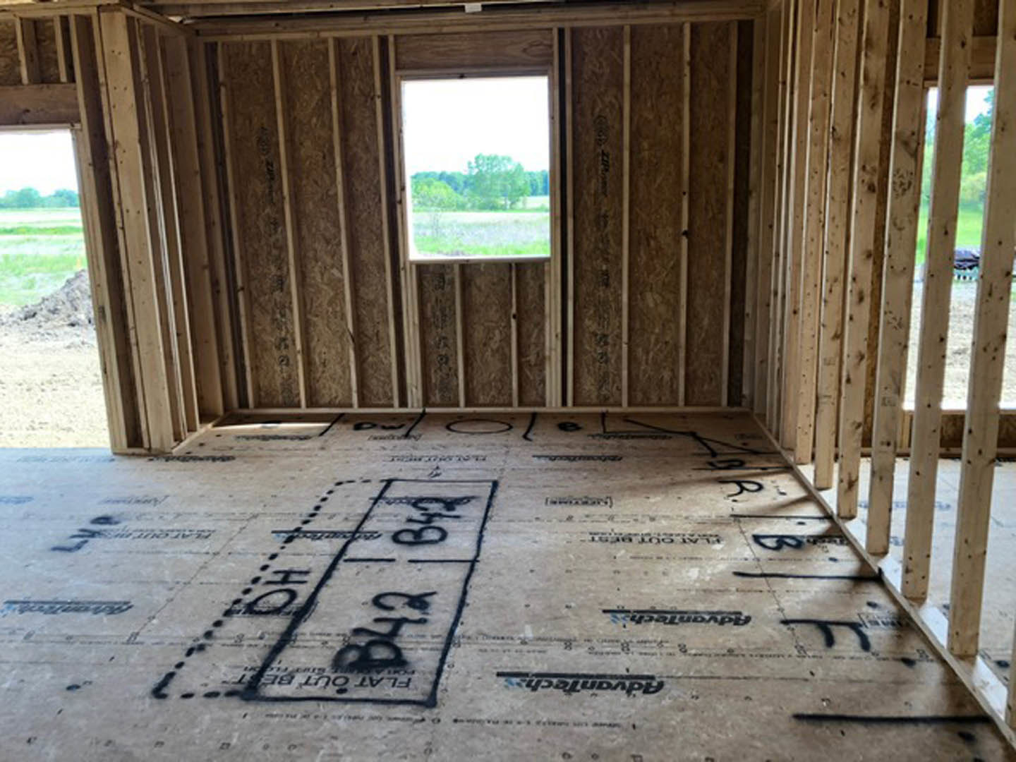 Concrete floor with handwritten black text, large window overlooking trees, wood plank walls, natural light filling the room