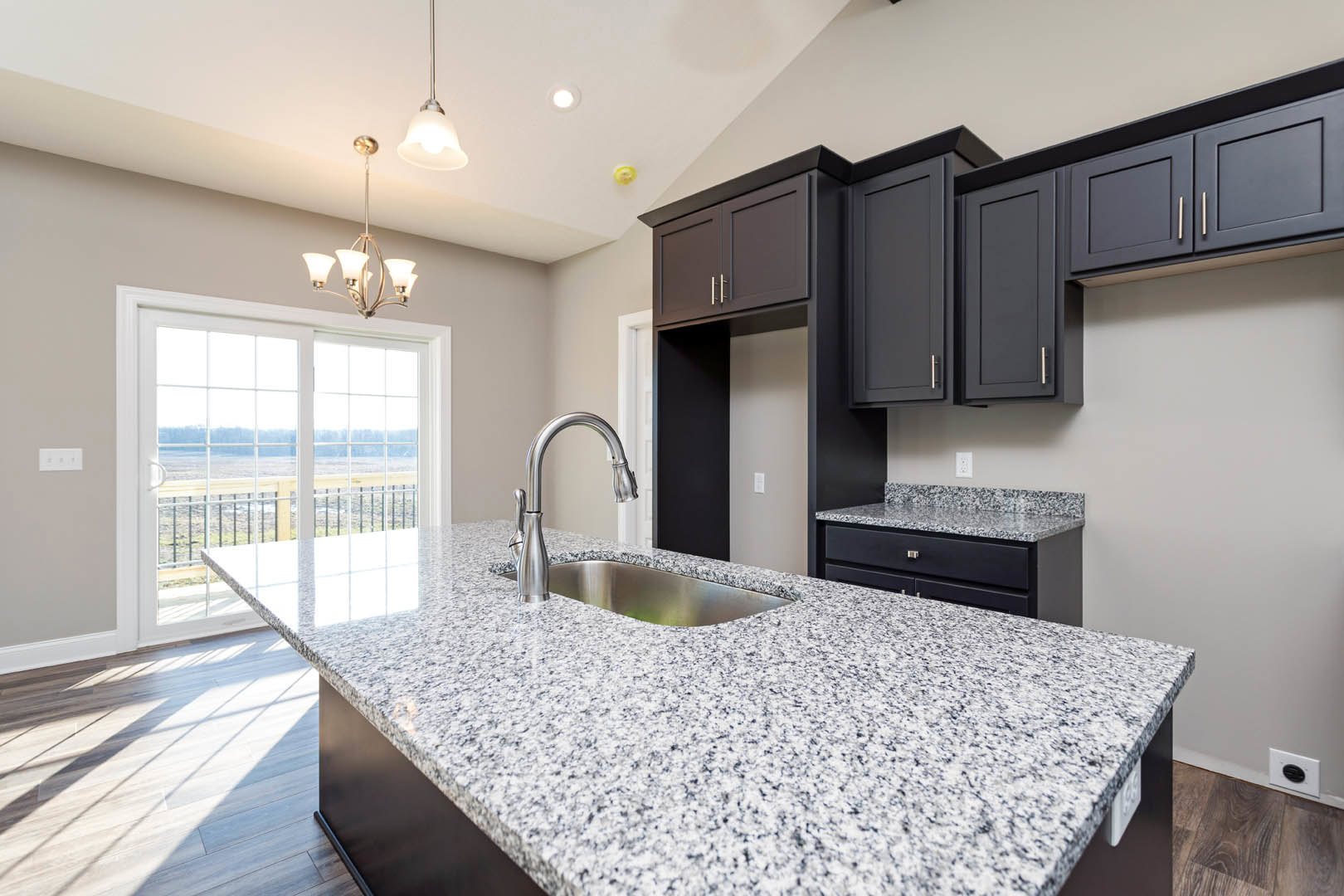 Granite countertop kitchen with stainless steel sink, chrome faucet, white cabinetry, tile backsplash, and a white door featuring glass window panes