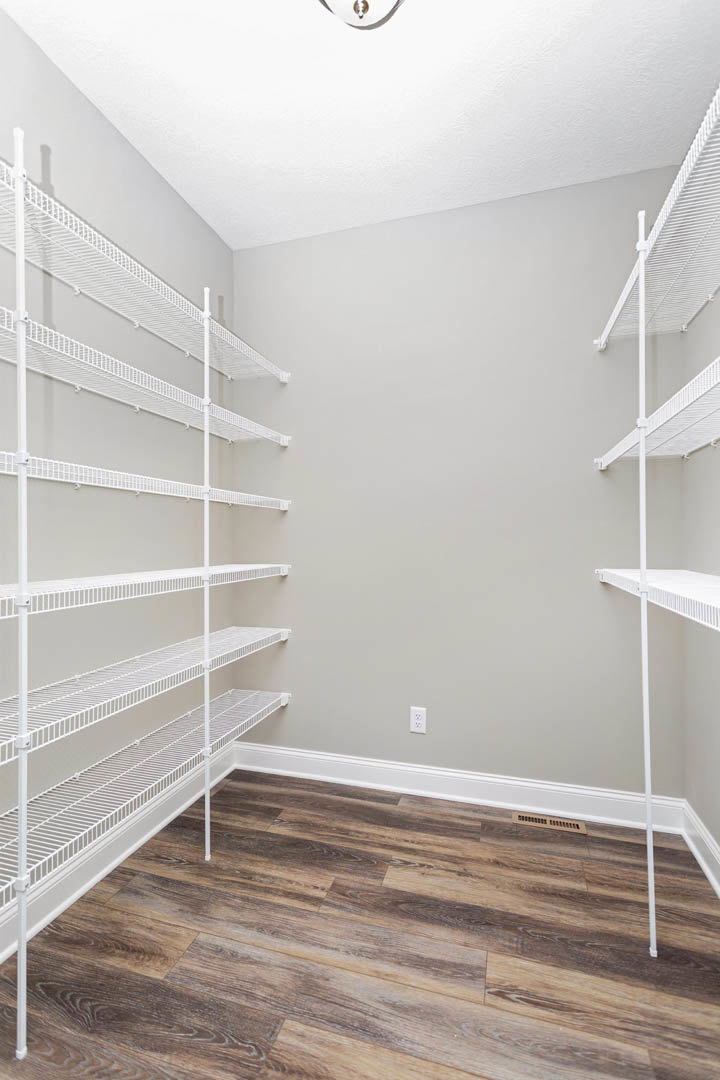 Hardwood floor room with built-in white shelving and white trim, empty closet space, plaster walls