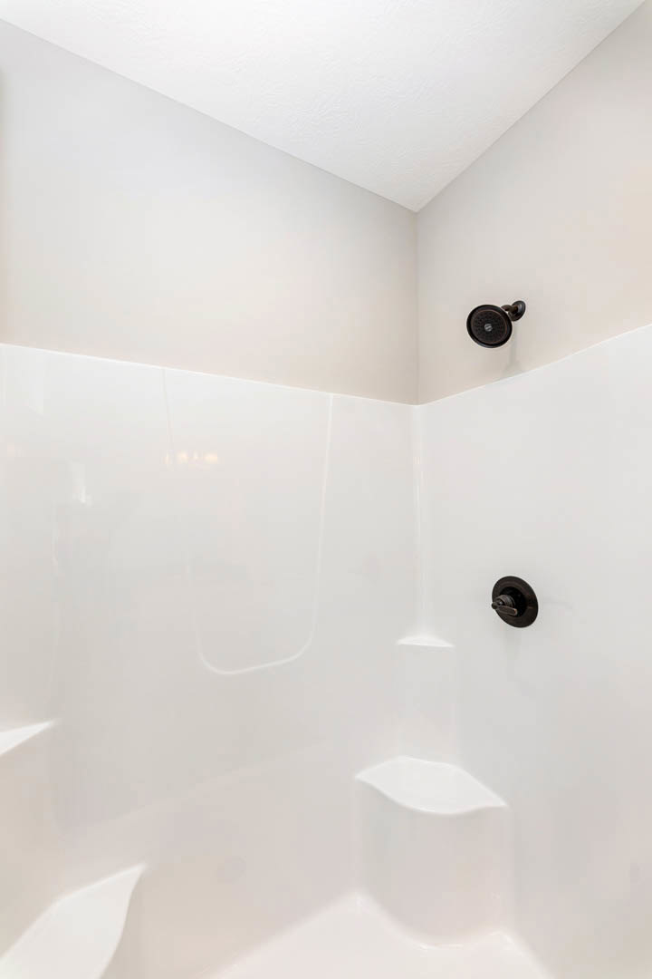 Modern bathroom with glass-enclosed shower, chrome shower head, freestanding white bathtub, plaster walls, and white ceiling