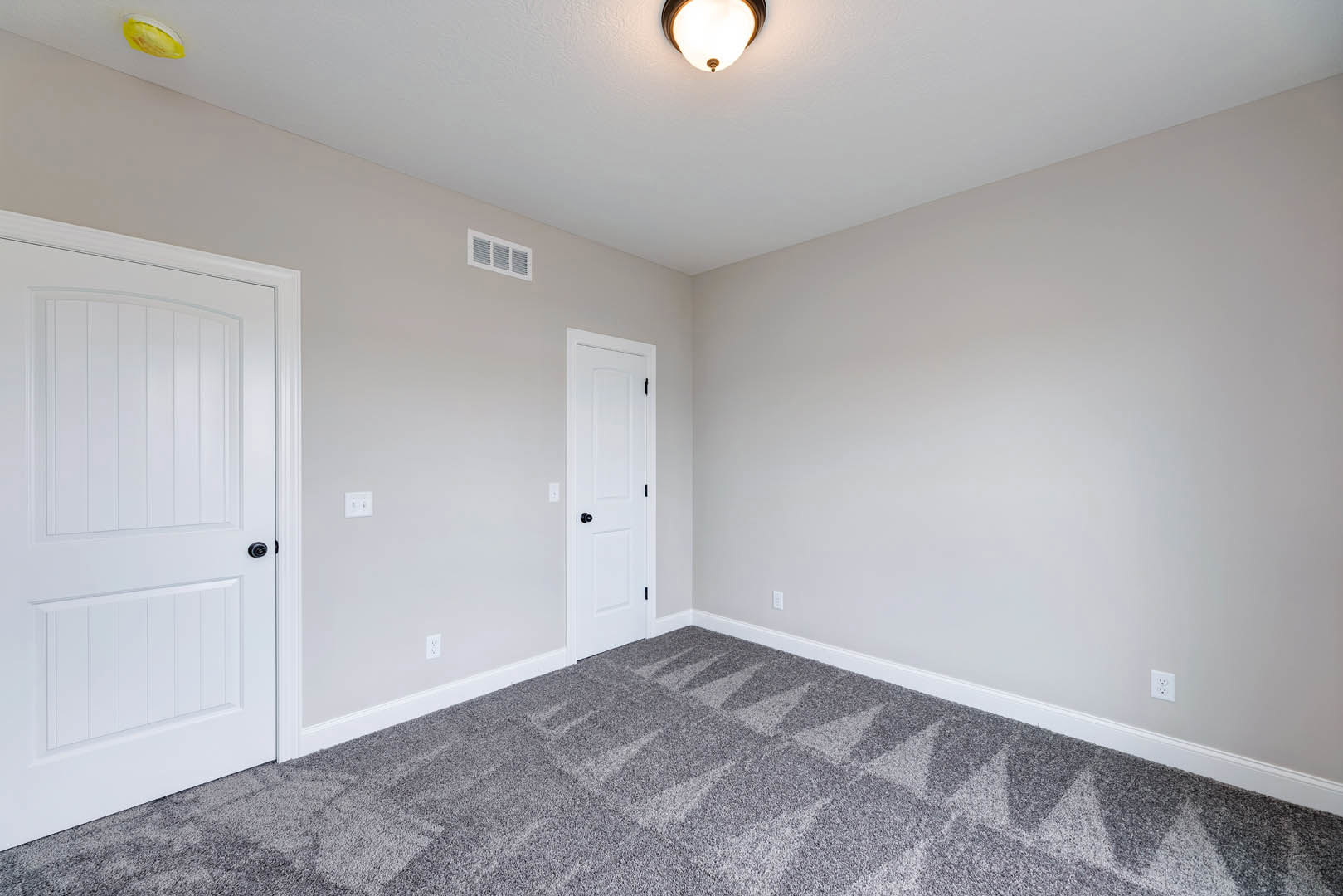 White paneled doors with black knobs, patterned grey carpet flooring, white plaster walls, and ceiling with recessed lighting