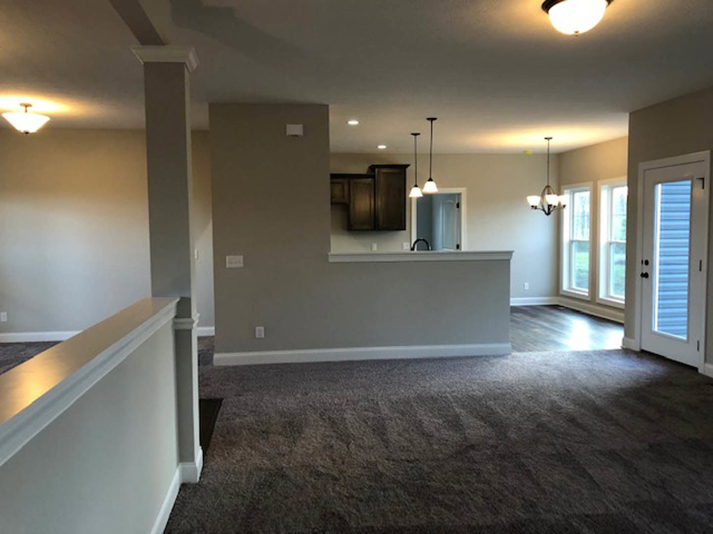 Open-concept living room with hardwood floors, modern kitchen cabinetry, dining area, recessed ceiling lights, and neutral wall finishes