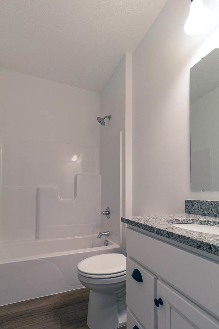 Modern bathroom featuring a white ceramic sink with chrome faucet, adjacent toilet, light gray tile flooring, and white painted walls.