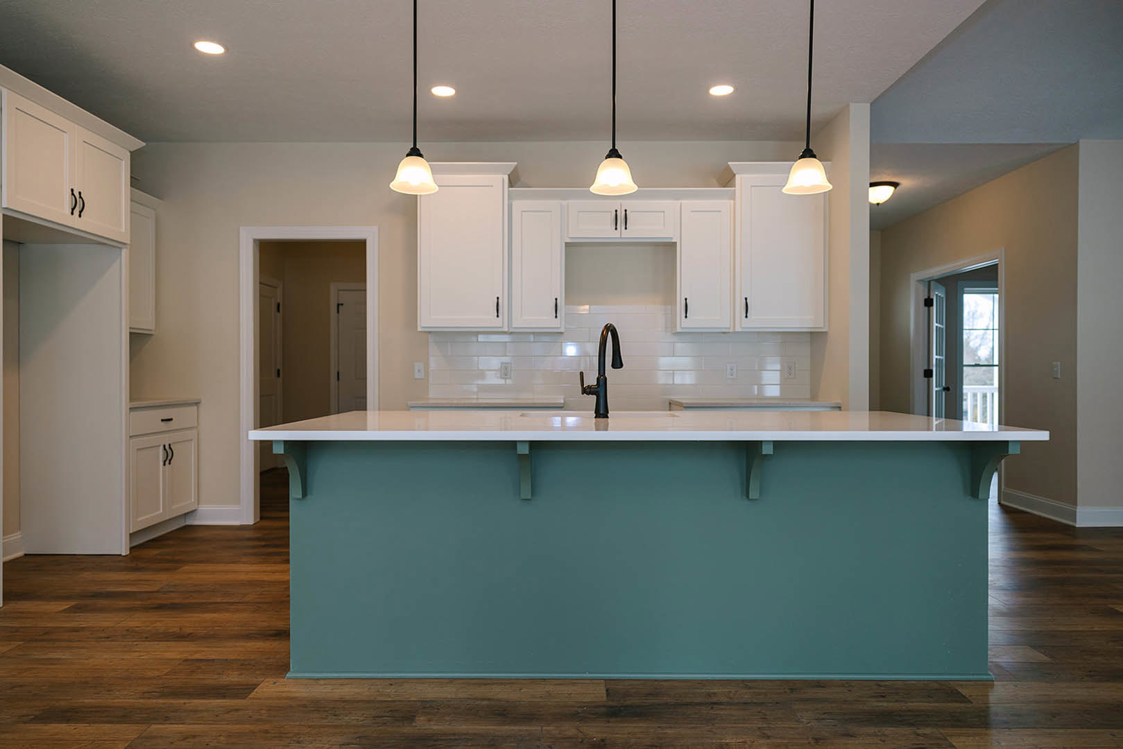 Kitchen with white cabinetry, white countertops, black faucet, white tile backsplash, bar seating, white door with black handle, black pendant light, white ceiling and walls