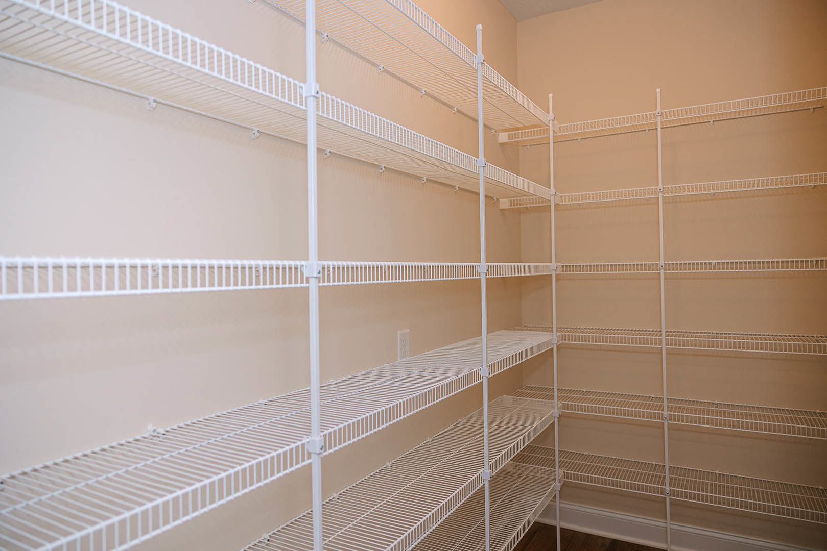 White wire shelving unit installed in an empty closet with smooth white walls and neutral flooring