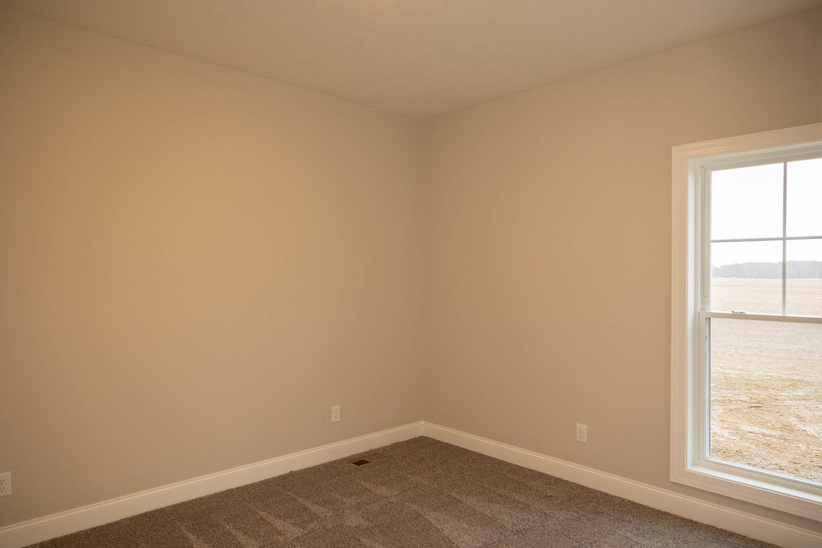Carpeted room with white walls, door, window overlooking a grassy field, floor vent, and window blinds