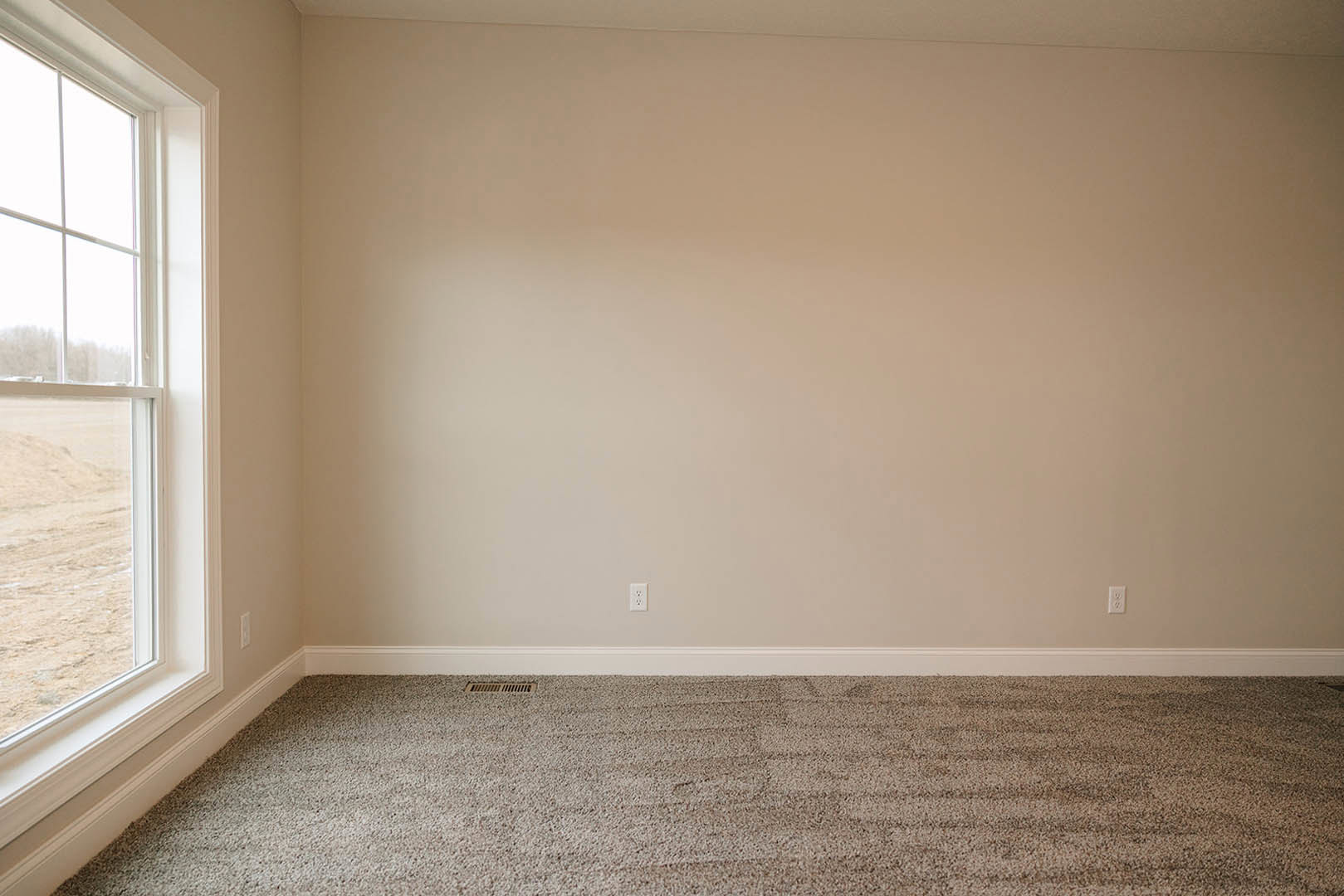 Carpeted floor, white walls and ceiling, large window with white blinds, black trim along baseboard