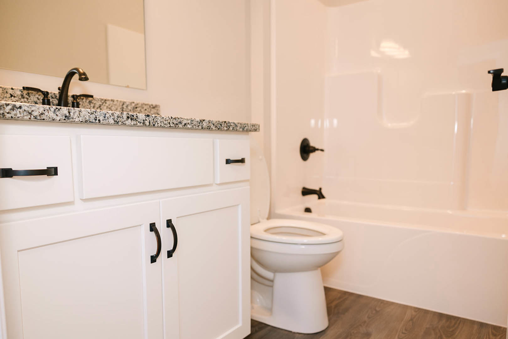 Bathroom featuring marble countertop, undermount sink, chrome faucet, white tile backsplash, and neutral wall paint