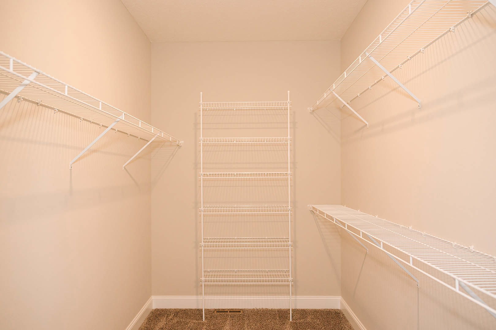 White wire shelving mounted on a white plaster wall in a small indoor room with visible ceiling and floor.