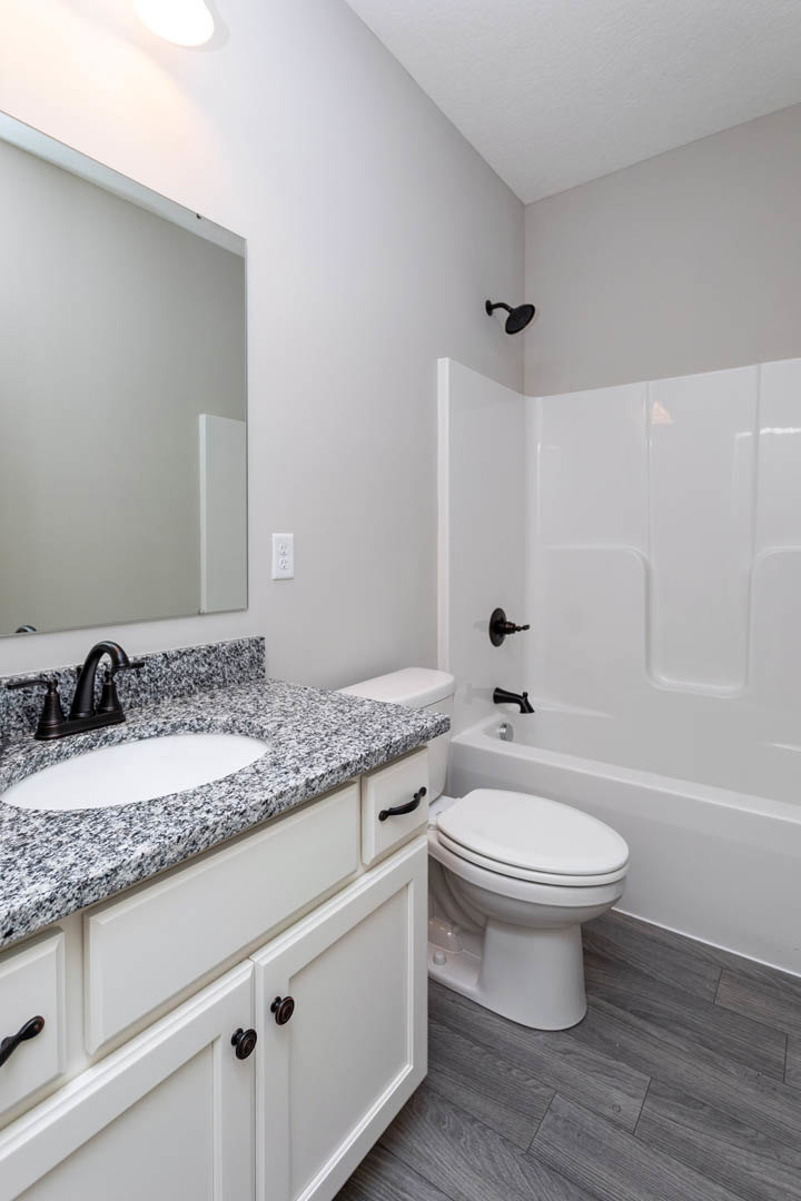 Modern bathroom featuring a white ceramic sink with chrome faucet, glass-enclosed shower, light wood flooring, and neutral tile walls