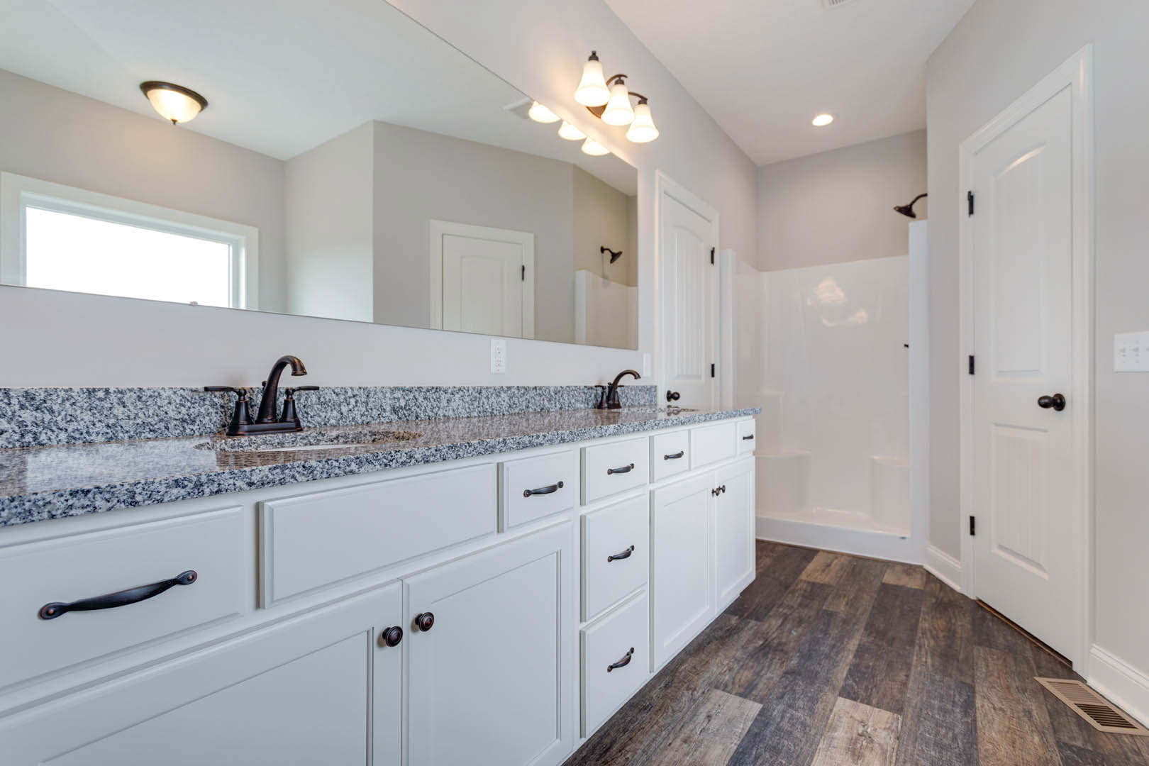 Bathroom featuring white cabinetry with black handles, marble countertops, chrome faucet, tile flooring, and a window providing natural light